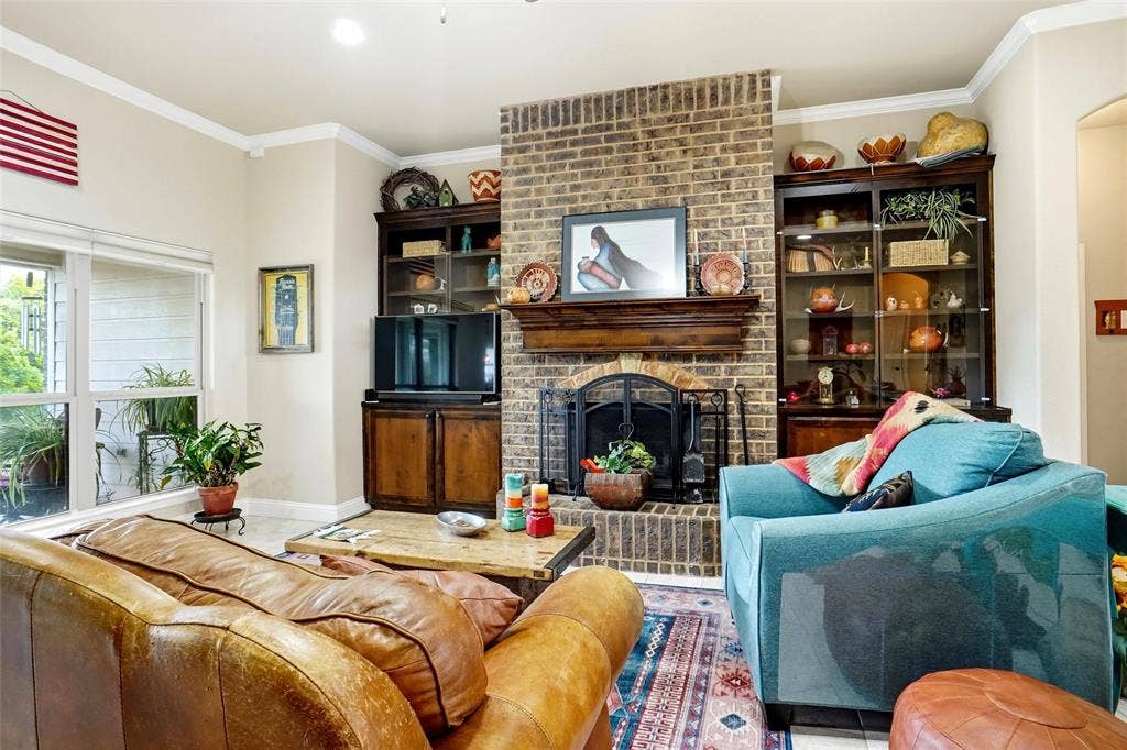 Floor-to-ceiling brick fireplace with a wood mantel and built-in cabinetry featuring glass-paneled display shelving