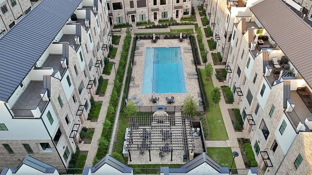 Central rectangular swimming pool, structured landscaping, paved walkways, and a covered outdoor seating area