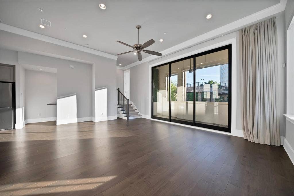 Wide-plank wood-finish flooring, recessed ceiling lighting, a ceiling fan, and black-framed sliding glass doors