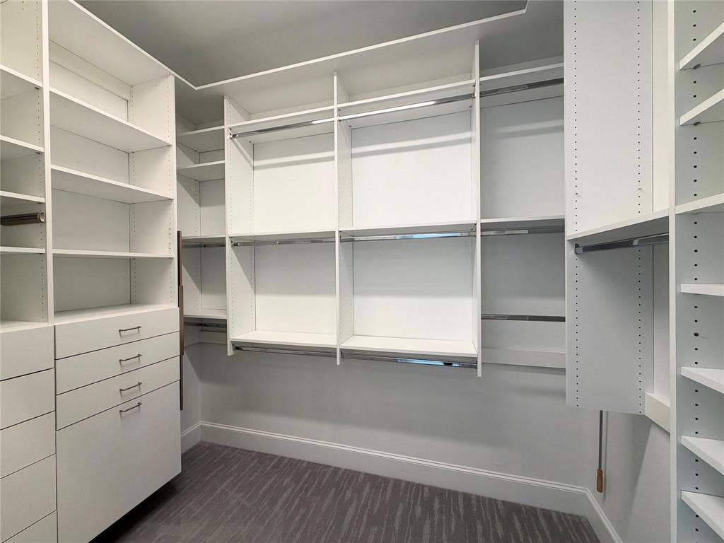 Custom built-in closet system with multiple shelving units, integrated drawers, hanging rods, and a patterned carpet