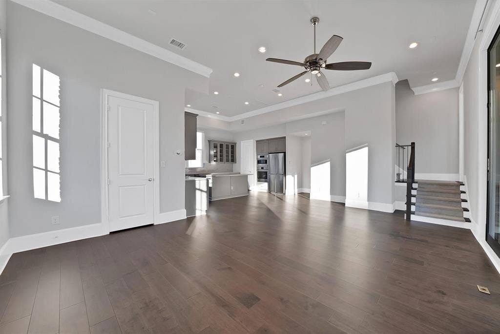 Hardwood-finish flooring, recessed lighting, ceiling fan, crown molding, and a staircase with a black metal railing