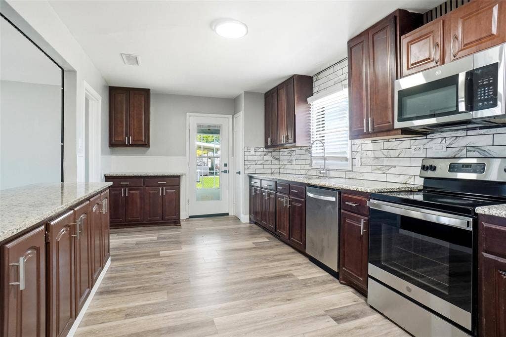 705 Vine Street, Euless, TX 76040 breakfast bar, loads of cabinets, granite counters, stainless appliances, coffee bar next to back door to covered back porch