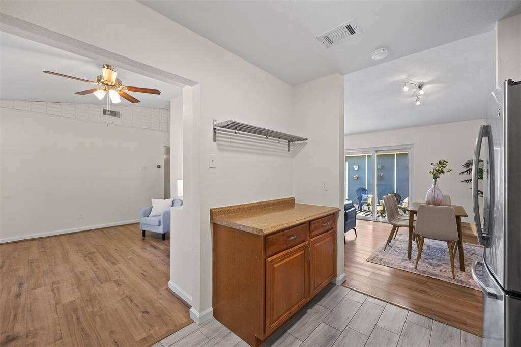 1118 Pacific Drive, Richardson, TX 75081 Wood-finish flooring throughout, wood cabinetry with countertop, track lighting, and sliding glass doors