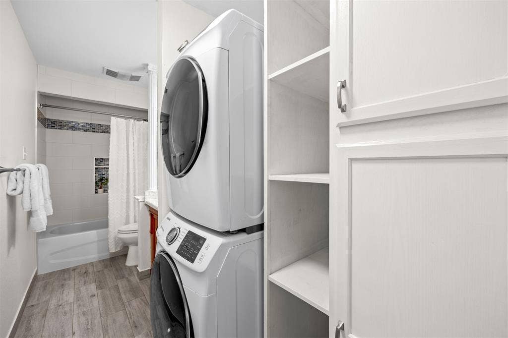 1118 Pacific Drive, Richardson, TX 75081 Dedicated laundry area with stacked appliances, white shaker-style cabinetry, and open shelving