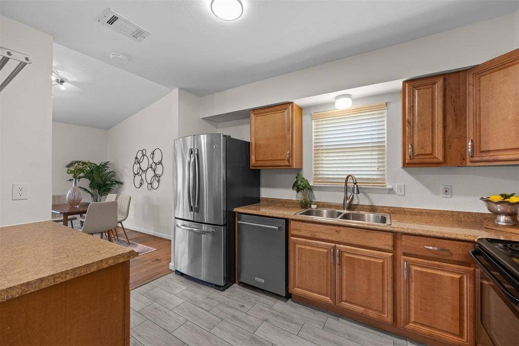 1118 Pacific Drive, Richardson, TX 75081 Updated kitchen featuring wood cabinetry, stone-look countertops, stainless steel appliances, and a double basin sink