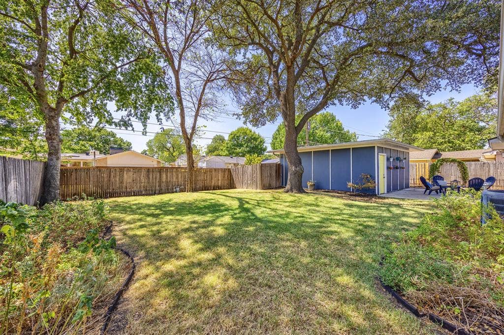 1118 Pacific Drive, Richardson, TX 75081 Spacious backyard featuring a manicured lawn, established shade trees, and a privacy fence