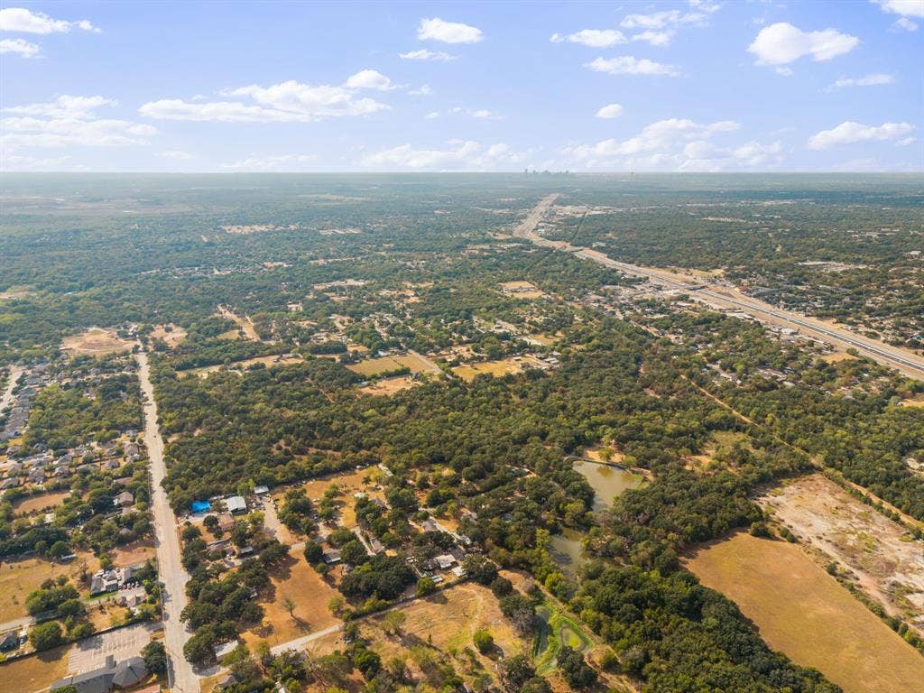 19 No Name Street, Dallas, TX 75217 Expansive tree coverage, visible roadway infrastructure, and a natural pond feature