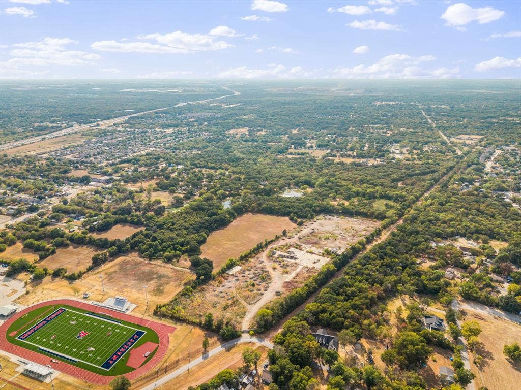19 No Name Street, Dallas, TX 75217 Expansive aerial perspective showcasing a football field with track, surrounding residential areas, and abundant mature trees