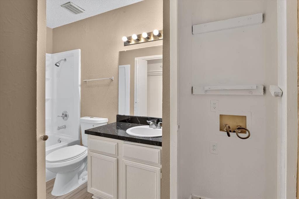 Bathroom with a white vanity, dark countertop, and integrated sink