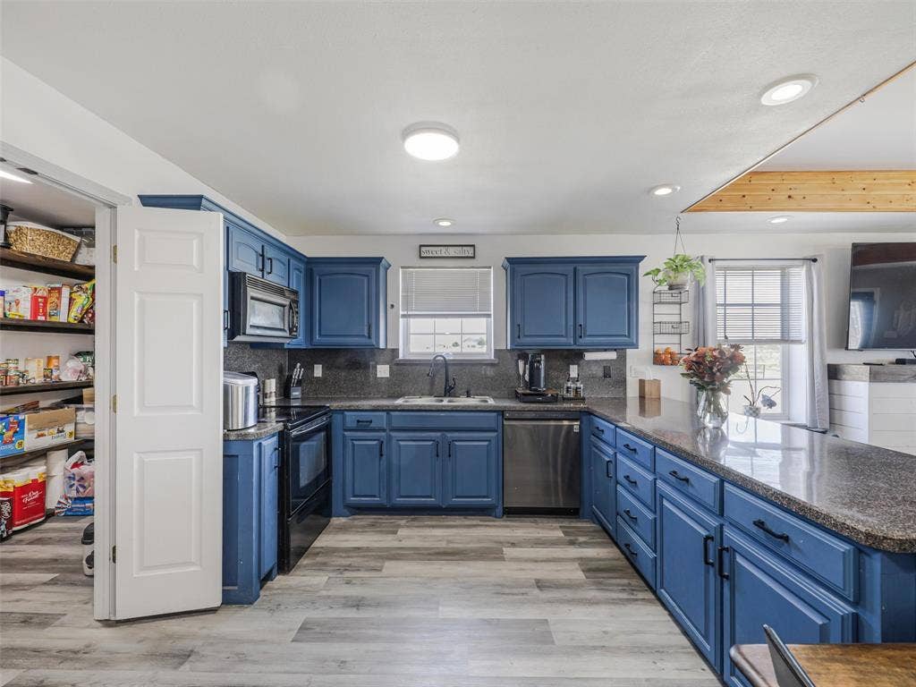 16880 W Fm 455, Celina, TX 75009 U-shaped kitchen featuring blue cabinetry, dark countertops, wood-finish flooring, and a walk-in pantry with shelving
