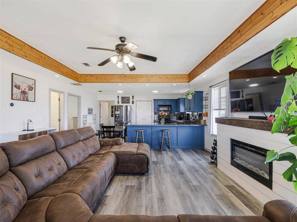 16880 W Fm 455, Celina, TX 75009 Exposed wood beams, ceiling fan with integrated lighting, wood-finish flooring, built-in fireplace, and blue cabinetry