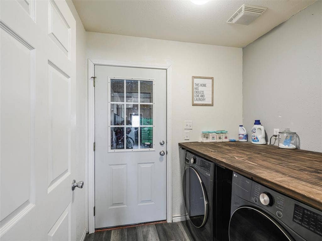 16880 W Fm 455, Celina, TX 75009 Dedicated laundry space featuring a wood-finish countertop, front-loading washer and dryer, and exterior access door
