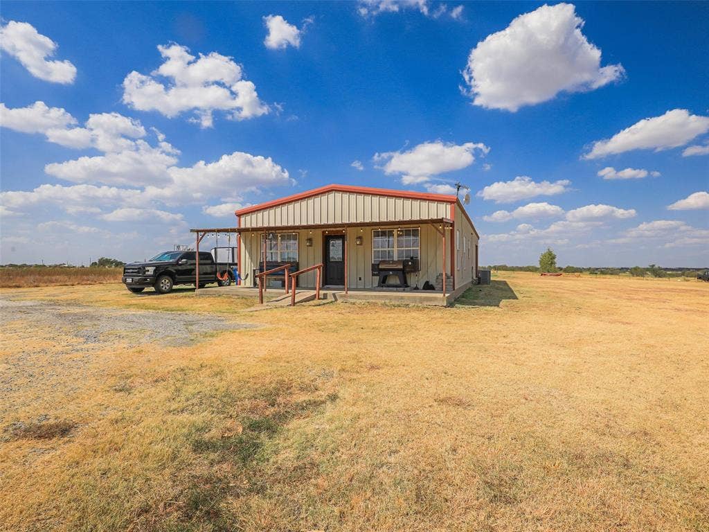 16880 W Fm 455, Celina, TX 75009 Metal-sided structure with a red roof, front porch, and an accessible ramp entry