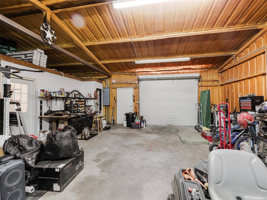 16880 W Fm 455, Celina, TX 75009 Garage with concrete flooring, wood paneling, exposed wood beam ceiling, and a large roll-up door