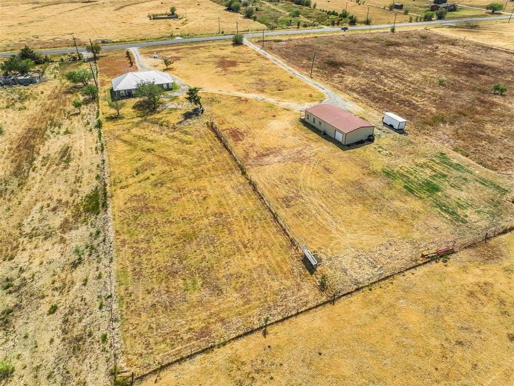 16880 W Fm 455, Celina, TX 75009 Expansive property featuring a single-story residence, a large outbuilding with a red roof, and established fencing