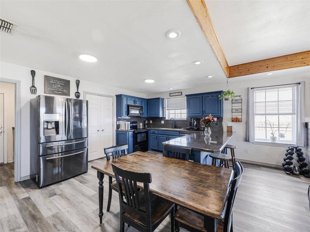16880 W Fm 455, Celina, TX 75009 Kitchen featuring blue cabinetry, dark countertops, a stainless steel refrigerator, and wood-finish flooring