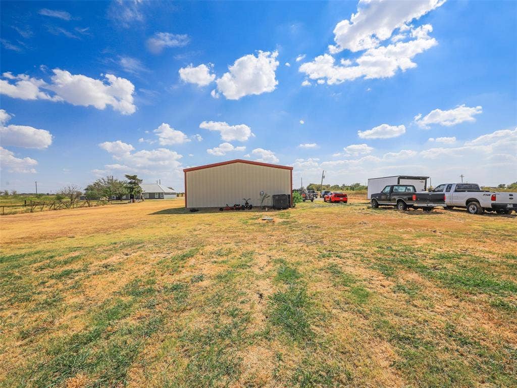 16880 W Fm 455, Celina, TX 75009 Expansive open land with a metal-sided utility building featuring a red roof