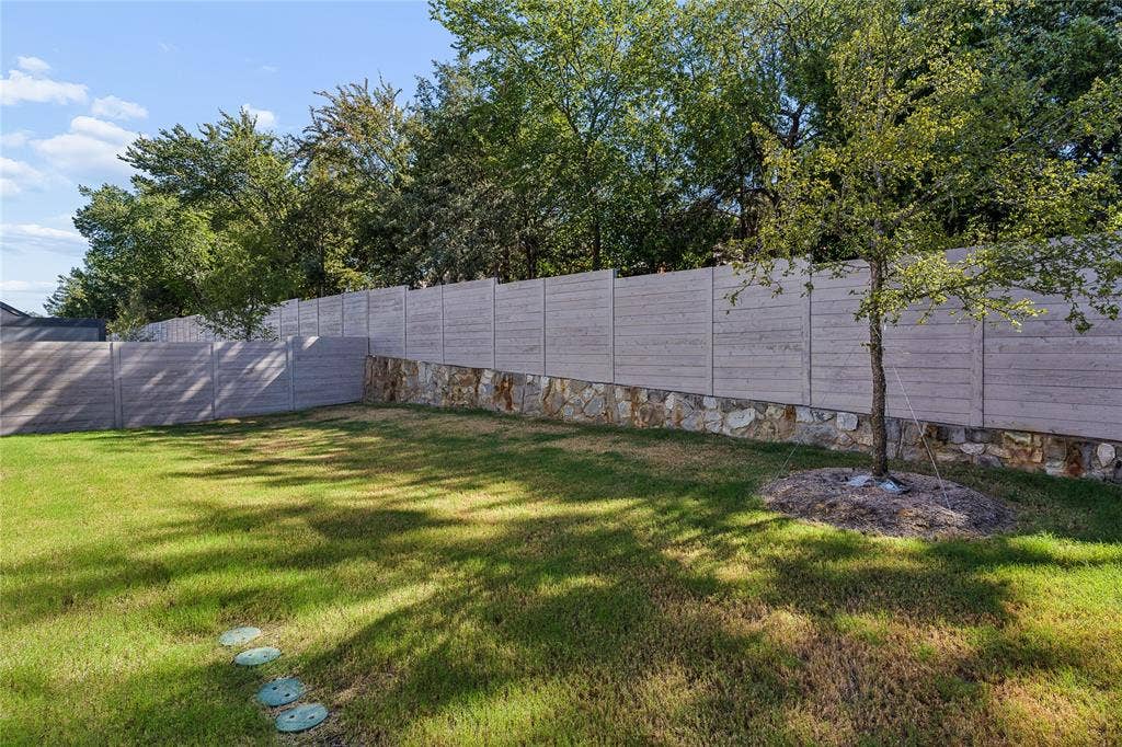 Expansive lawn with a stone retaining wall and a privacy fence