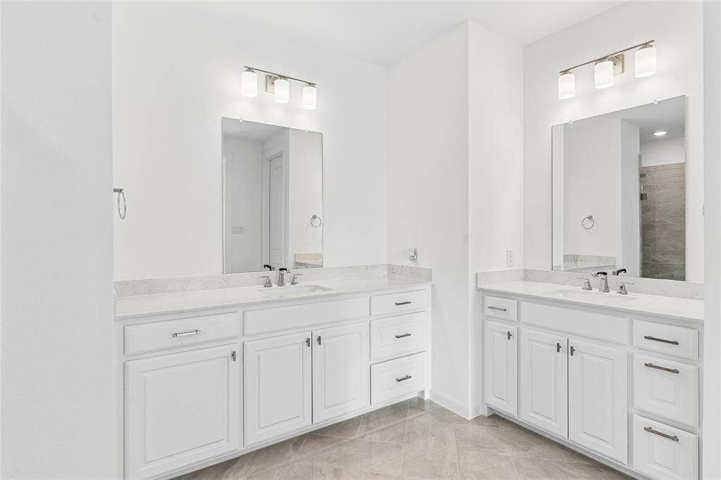Dual vanity sinks with white cabinetry and stone countertops