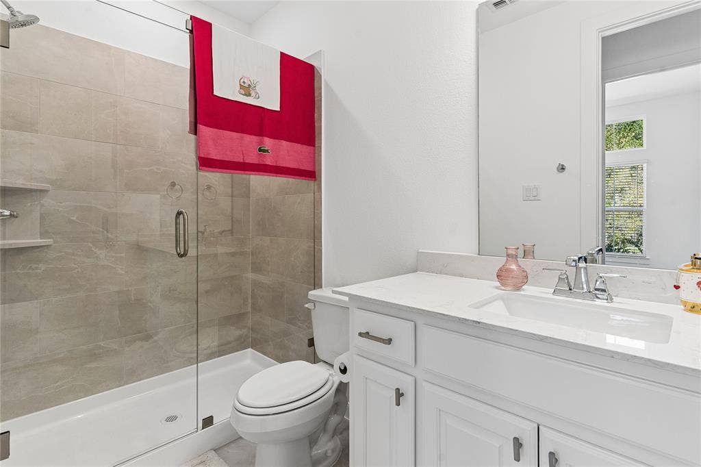 Glass-enclosed shower with tiled surround, built-in shelving, and rain showerhead