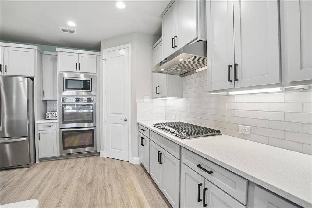 2206 Wellington Lane, Corinth, TX 76210 Beautiful kitchen featuring built in gas cooktop, double ovens, quartz countertops and abundant cabinetry.