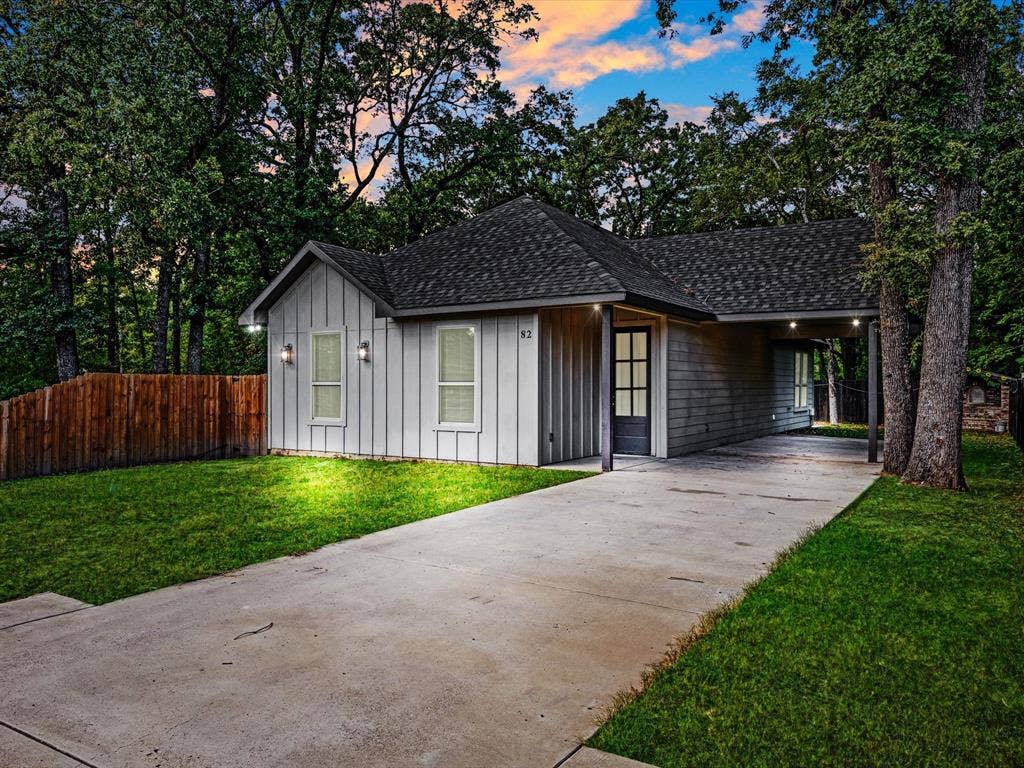 82 Indian Harbor Drive, Mabank, TX 75156 Board and batten siding, dark shingle roof, attached carport, concrete driveway, and a wood privacy fence