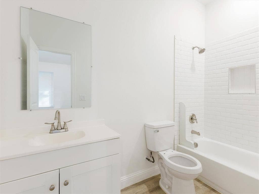 82 Indian Harbor Drive, Mabank, TX 75156 White vanity with an integrated sink, brushed nickel faucet, a frameless wall mirror, subway tile shower surround, and built-in shower niche