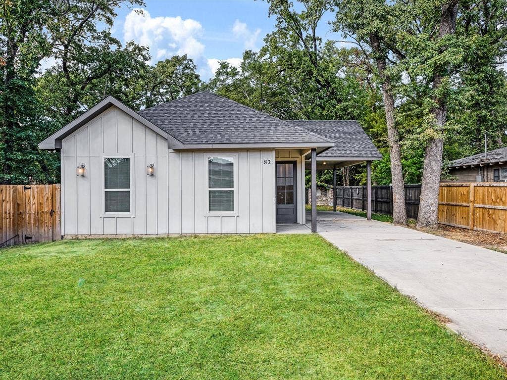 82 Indian Harbor Drive, Mabank, TX 75156 Gabled roofline, board and batten siding, covered carport, concrete driveway, and wooden privacy fencing