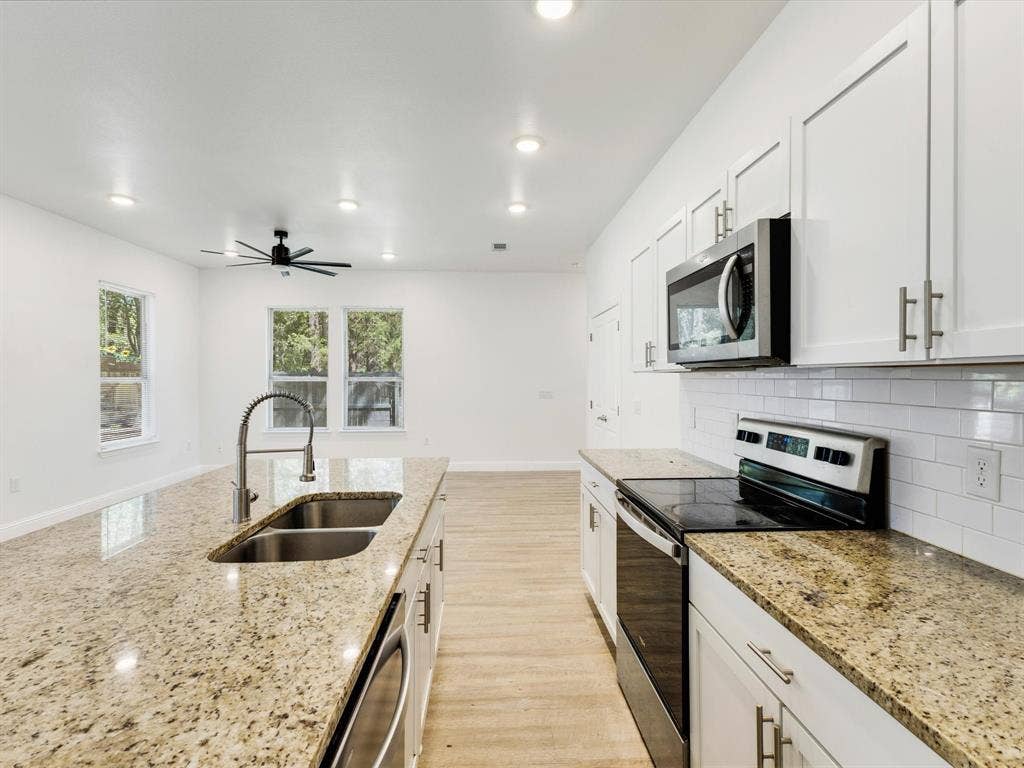 82 Indian Harbor Drive, Mabank, TX 75156 Kitchen featuring granite countertops, a double basin stainless steel sink with a high-arc faucet, white subway tile backsplash, and white cabinetry with brushed nickel hardware