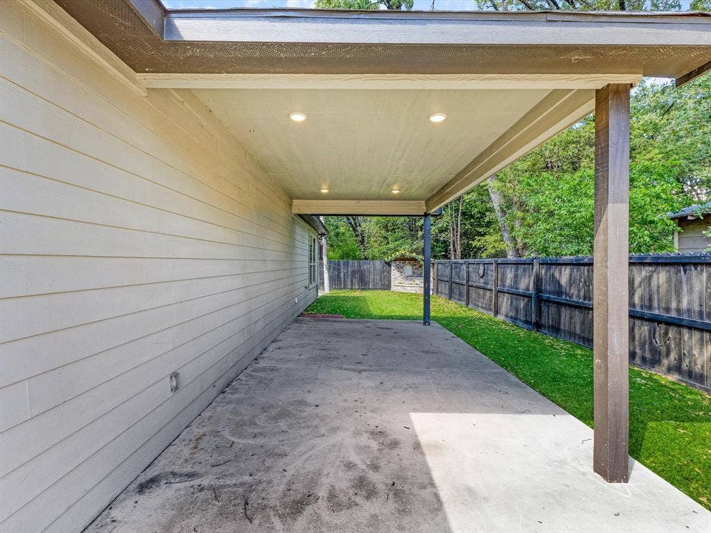 82 Indian Harbor Drive, Mabank, TX 75156 Covered concrete patio with recessed lighting, bordered by a wood privacy fence and green lawn