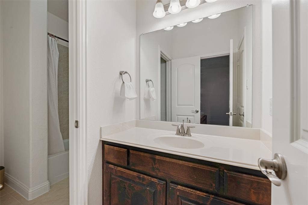 2408 Brisbane Lane, Plano, TX 75075 Jack and Jill Bathroom. Vanity with a wood-finish cabinet, light-colored countertop, and integrated sink