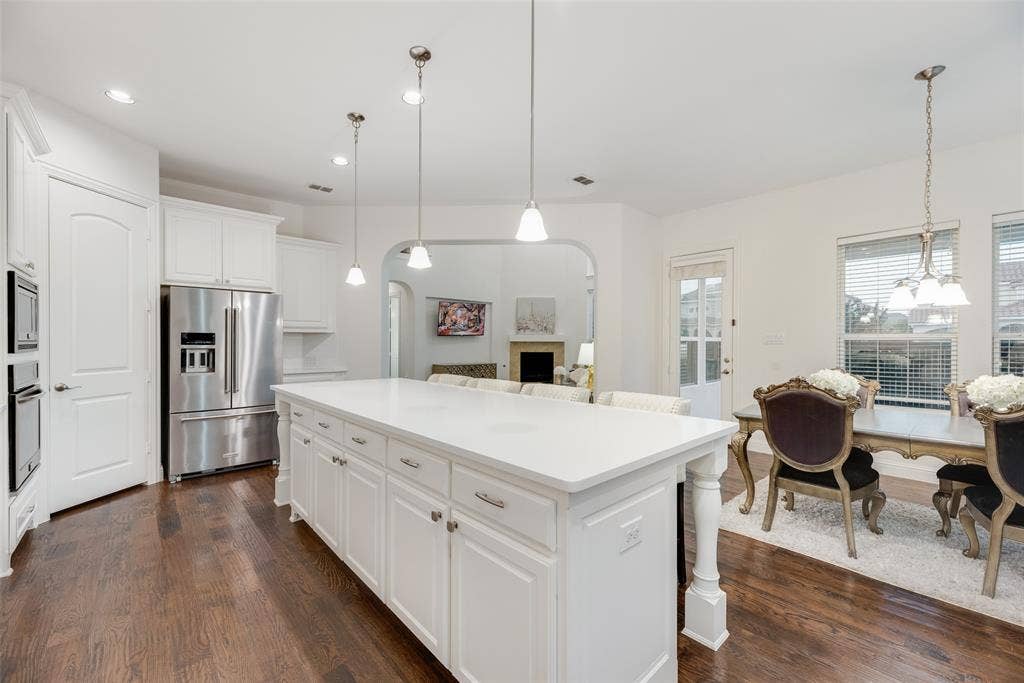 2408 Brisbane Lane, Plano, TX 75075 Kitchen featuring an expansive center island with white cabinetry, stainless steel appliances, and dark wood-finish flooring
