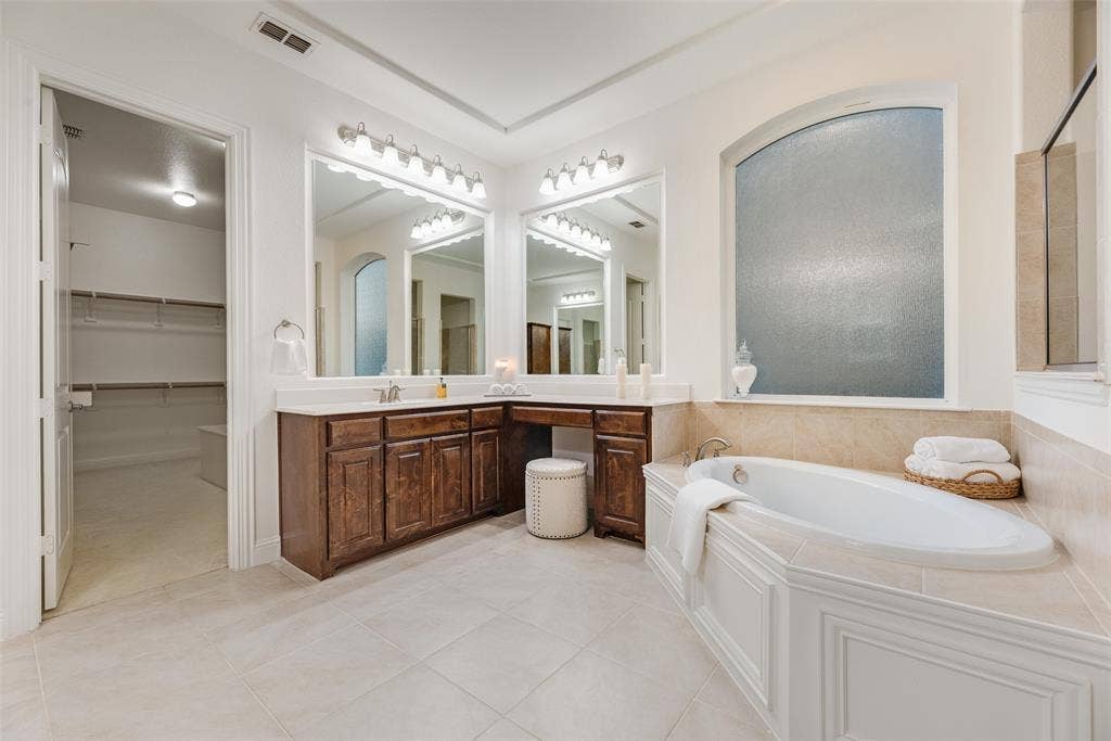 2408 Brisbane Lane, Plano, TX 75075 Tile flooring, built-in bathtub, dual vanity with wood cabinetry, and a privacy window