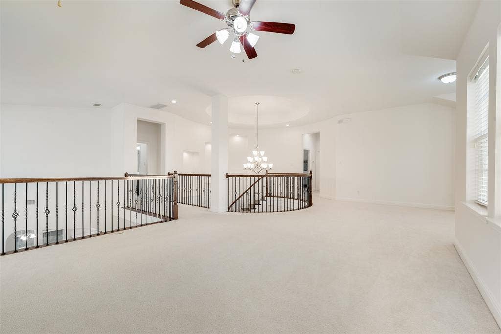 2408 Brisbane Lane, Plano, TX 75075 Expansive carpeted loft area featuring an ornate chandelier, recessed lighting, a ceiling fan, and decorative wrought iron and wood railings