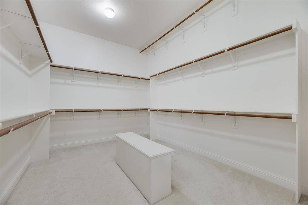 2408 Brisbane Lane, Plano, TX 75075 Spacious walk-in closet featuring extensive built-in shelving, multiple hanging rods, and light-toned carpeting