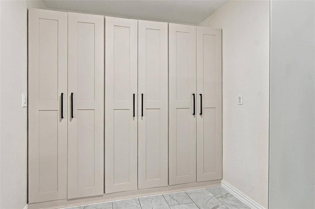 4720 Kyle Drive, Balch Springs, TX 75180 Built-in cabinetry with flat panel doors and matte black hardware, set against light-toned walls and patterned flooring