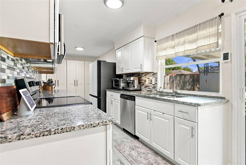 4720 Kyle Drive, Balch Springs, TX 75180 White cabinetry, speckled countertops, tile backsplash, stainless steel dishwasher, and a sliding glass door