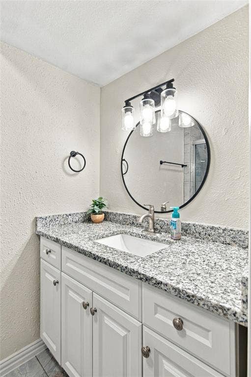 4720 Kyle Drive, Balch Springs, TX 75180 White vanity with paneled doors, speckled countertop, undermount sink, and brushed nickel faucet