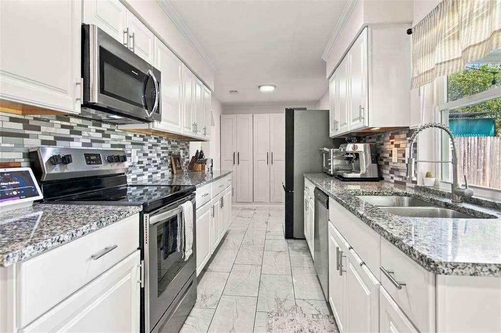 4720 Kyle Drive, Balch Springs, TX 75180 Galley kitchen featuring white cabinetry, granite-finish countertops, mosaic tile backsplash, and stainless steel appliances
