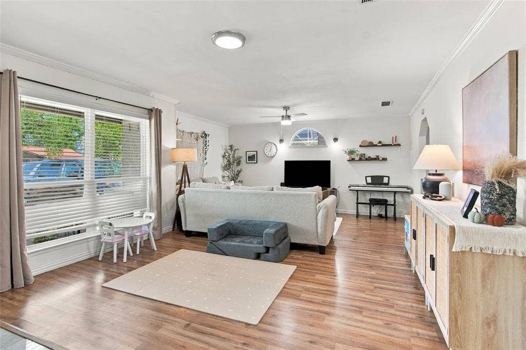 4720 Kyle Drive, Balch Springs, TX 75180 Wood-finish flooring, white walls, crown molding, a large window with blinds, and recessed lighting fixtures