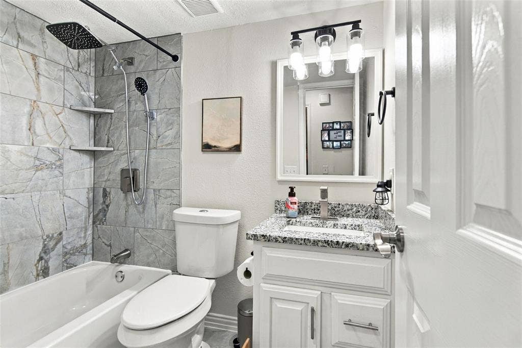 4720 Kyle Drive, Balch Springs, TX 75180 Shower/tub combination with gray stone-look tile surround and built-in shelving