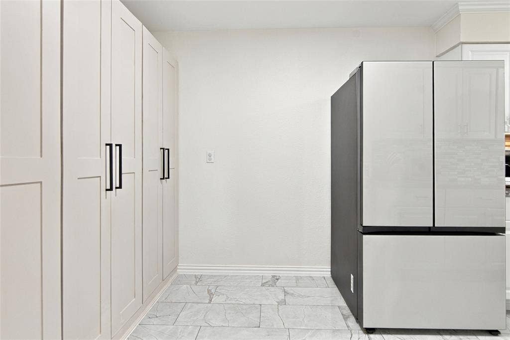 4720 Kyle Drive, Balch Springs, TX 75180 Full-height cabinetry with matte black hardware, contemporary refrigerator with a black side panel, white walls, and light-toned tile flooring