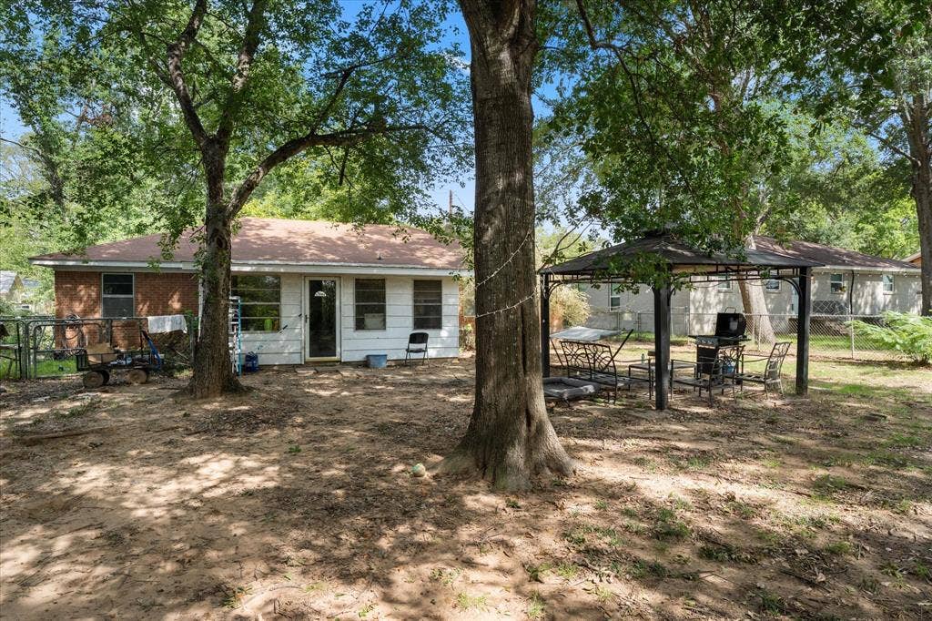 402 E Cook Street, Eustace, TX 75124 Spacious backyard featuring mature trees and a metal-frame gazebo structure