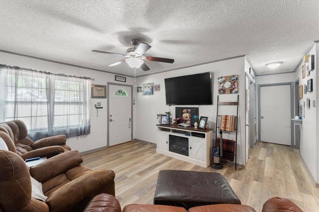 402 E Cook Street, Eustace, TX 75124 Wood-finish flooring, ceiling fan with integrated lighting, multi-panel front door with glass insert, and neutral wall tones