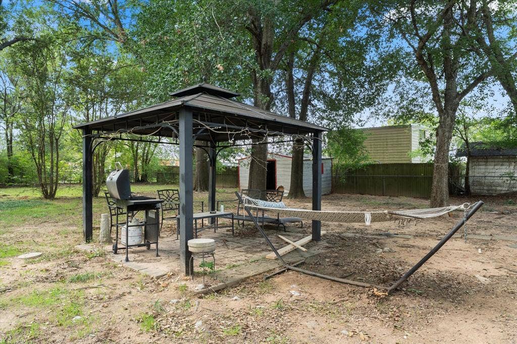 402 E Cook Street, Eustace, TX 75124 Outdoor space featuring a metal-framed gazebo with a peaked roof, concrete patio, and mature trees