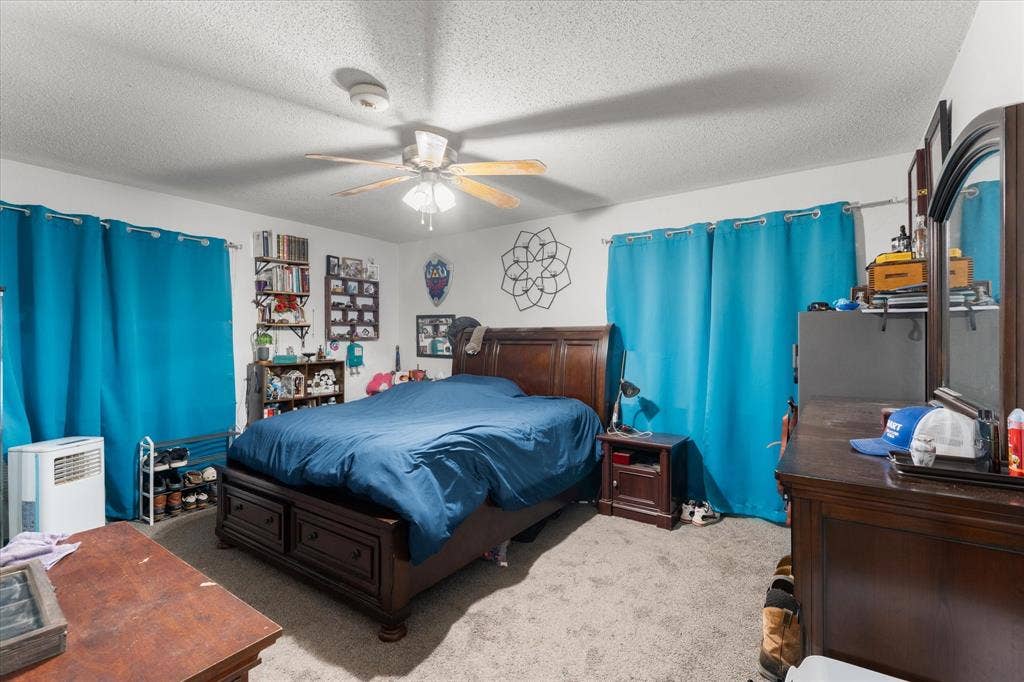 402 E Cook Street, Eustace, TX 75124 Neutral-toned wall finish featuring a central ceiling fan with integrated lighting and wall-to-wall carpeting