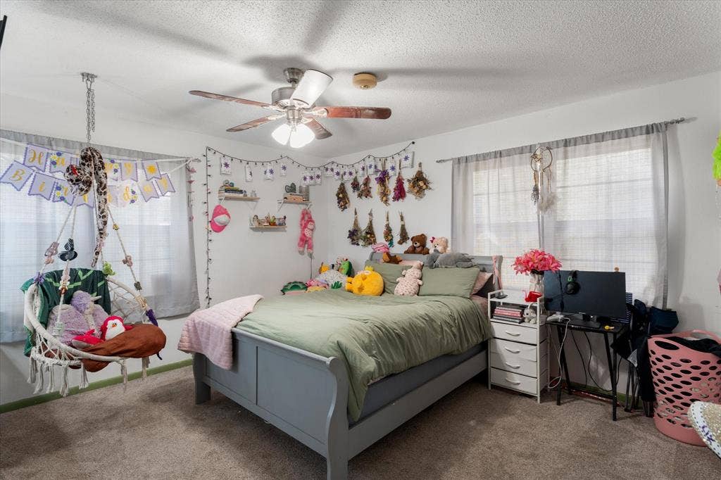 402 E Cook Street, Eustace, TX 75124 Room featuring neutral wall-to-wall carpeting, dual windows with soft-filter window treatments, and a central ceiling fan with integrated lighting