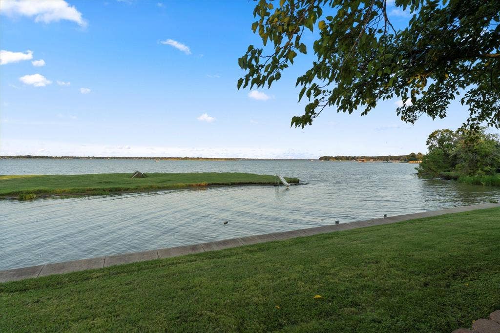 308 Causeway Cove, Seven Points, TX 75143 Waterfront property featuring a concrete retaining wall, a grassy lawn, and mature trees