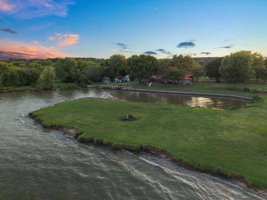 308 Causeway Cove, Seven Points, TX 75143 Waterfront property featuring a grassy peninsula, mature trees, and a retaining wall along the water's edge