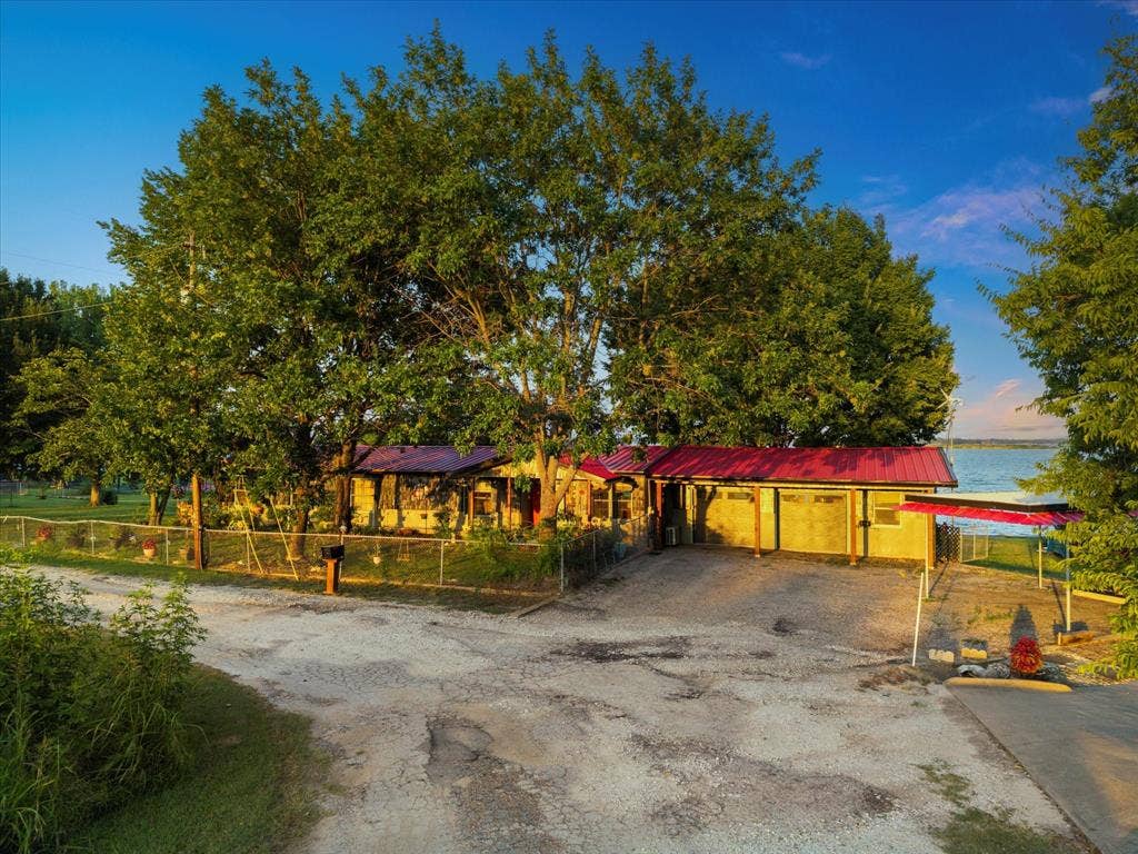 308 Causeway Cove, Seven Points, TX 75143 Red metal roofing accents the structure with a water backdrop